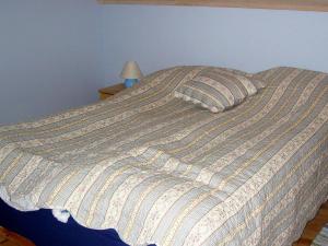 a bed with a striped comforter and a pillow at 6 person holiday home in ALSV G in Gisløy
