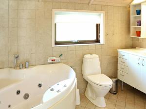 a bathroom with a tub and a toilet and a window at 7 person holiday home in Ulfborg in Sønder Nissum