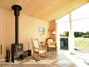 a living room with a wood stove and a chair at 8 person holiday home in Fan in Fanø