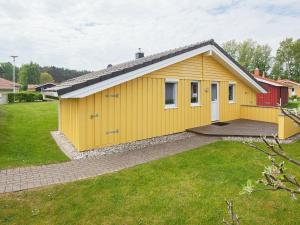 een geel huis met een rood gebouw in een tuin bij 6 person holiday home in GROEMITZ in Grömitz