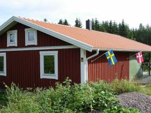 una casa roja con banderas a un lado. en 8 person holiday home in GR NNA, en Målskog