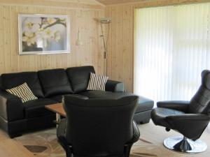 un soggiorno con divano nero e 2 sedie di 6 person holiday home in Silkeborg a Engesvang