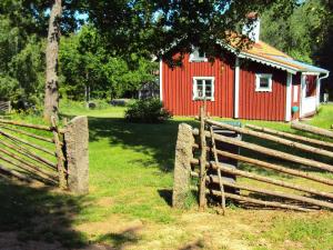 een rode schuur met een hek ervoor bij Two-Bedroom Holiday home in Lessebo in Skruv