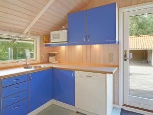a blue kitchen with a sink and a microwave at 6 person holiday home in Hemmet in Falen