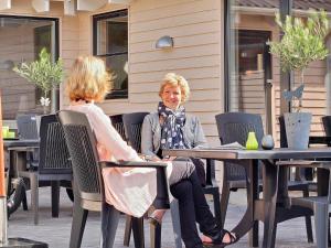 Dos mujeres sentadas en una mesa en un café al aire libre en 22 person holiday home in Sydals, en Sønderby