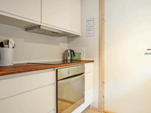 a small kitchen with white cabinets and a stove at 4 person holiday home in Gudhjem in Gudhjem