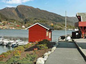 ein kleines rotes Gebäude neben einem Wasserkörper in der Unterkunft Holiday Home Sørbøvåg II in Sørbø