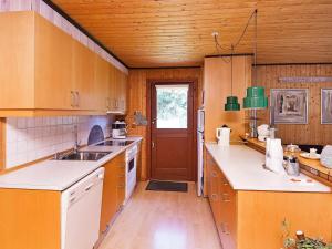 a kitchen with wooden cabinets and a wooden door at 6 person holiday home in R m in Bolilmark