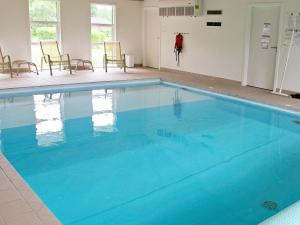 uma grande piscina azul num quarto com cadeiras em 8 person holiday home in Hals em Hals