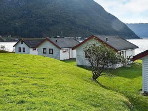 uma fila de casas numa colina relvada junto a um lago em 7 person holiday home in Selje em Selje