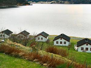 7 person holiday home in Selje في Selje: مجموعة من البيوت على شاطئ جسم ماء