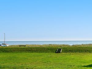 a bench in a field with the ocean in the background at 6 person holiday home in Juelsminde in Sønderby