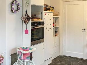 ロービュにある6 person holiday home in R dbyのキッチン(白い冷蔵庫、ピンクの椅子付)