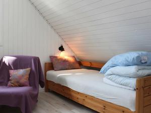 um quarto com uma cama e uma cadeira num quarto em Three-Bedroom Holiday home in Vejby 14 em Blåvand