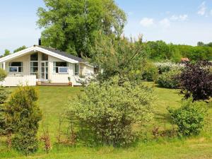 una pequeña casa blanca con un patio con arbustos en Holiday Home Skovløbervej en Rude