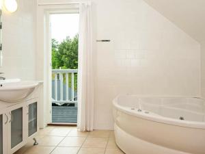 a white bathroom with a tub and a sink at 8 person holiday home in Gjern in Gjern