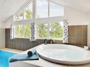 La salle de bains est pourvue d'une grande baignoire et de fenêtres. dans l'établissement 18 person holiday home in Bl vand, à Blåvand