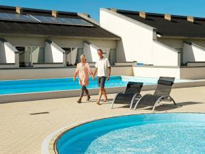 a man and a woman walking by a swimming pool at Apartment Brovst II in Brovst