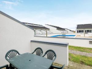 a green table and chairs on a balcony with a pool at 6 person holiday home in Brovst-By Traum in Brovst