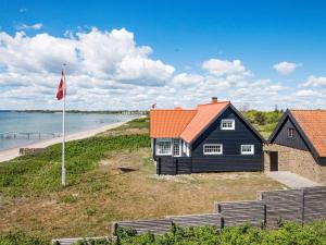 ヒュールスミンネにある5 person holiday home in Juelsmindeの海辺のオレンジ色の屋根の黒い家