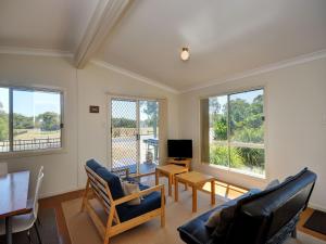 a living room with a couch and a table and two windows at Coastal Cottage in Hawks Nest