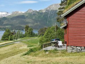 a red house with a wooden deck next to a building at Holiday Home Hjalmarhytta in Søre Birkedal