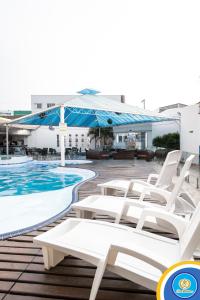 a group of white lounge chairs next to a swimming pool at Don Charleaux Hotel in Aparecida