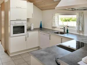 a kitchen with white cabinets and a sink and a window at 8 person holiday home in V ggerl se in Marielyst
