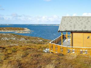 a wooden house on a hill next to the ocean at Three-Bedroom Holiday home in Dyrvik in Tuvnes