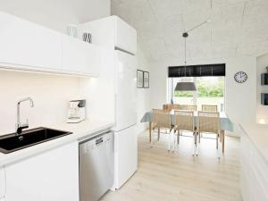 a kitchen with white cabinets and a table with chairs at Three-Bedroom Holiday home in Tarm 12 in Hemmet