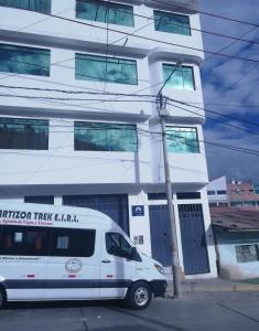 una furgoneta blanca estacionada frente a un edificio en Artesonraju Hostel Huaraz, en Huaraz