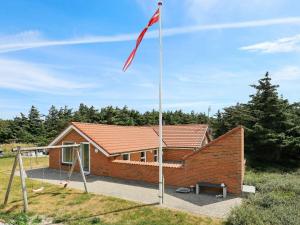 a flag pole in front of a brick house at 8 person holiday home in Harbo re in Harboør
