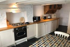 a kitchen with white cabinets and a black stove at Leatside Cottage in Port Isaac