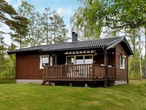 a wooden cabin with a large deck in a yard at Two-Bedroom Holiday home in Frändefors 1 in Stora Lövnäs