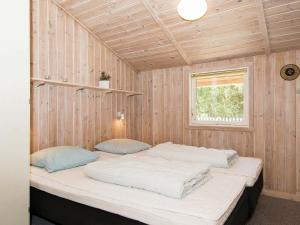 a bedroom with two beds in a wooden wall at Holiday Home Trinnesvej in Bolilmark