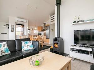 a living room with a black leather couch and a wood stove at 6 person holiday home in Hvide Sande in Hvide Sande