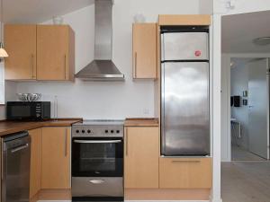 a kitchen with wooden cabinets and a stainless steel refrigerator at 6 person holiday home in Hvide Sande in Hvide Sande