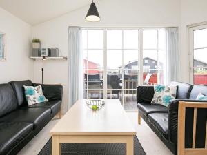 a living room with black leather couches and a table at 6 person holiday home in Hvide Sande in Hvide Sande