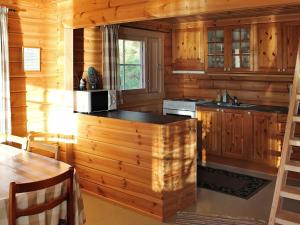 a kitchen with wooden walls and a stove and a table at 5 person holiday home in VÅGLAND in Bårdset