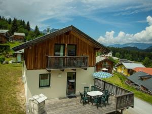 a house with a deck with a table and chairs at Chalet in Annaberg-Lungötz with a community pool in Annaberg im Lammertal