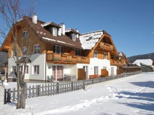 ein großes Holzhaus mit einem Zaun im Schnee in der Unterkunft Apartment in Sankt Margarethen near ski area in Sankt Margarethen im Lungau