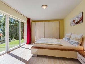 Schlafzimmer mit einem Bett und großen Fenstern in der Unterkunft Villa Angerberg in Piesendorf