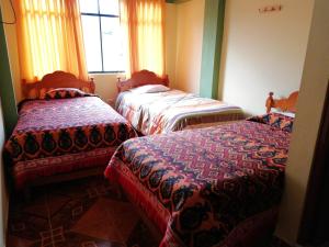 3 camas en una habitación con ventana en Artesonraju Hostel Huaraz, en Huaraz