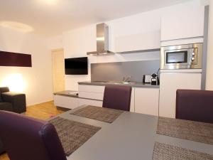 eine Küche mit einem Tisch mit Stühlen und einer Mikrowelle in der Unterkunft Cozy Apartment near Ski Area in Eisenerz in Eisenerz