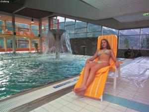 a woman in a bikini sitting on a chair next to a swimming pool at Cozy Apartment near Ski Area in Eisenerz in Eisenerz