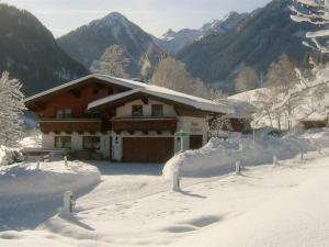 een huis bedekt met sneeuw met bergen op de achtergrond bij Cozy holiday apartment with sauna in Schladming in Schladming