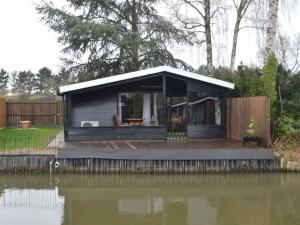 ein winziges Haus auf einem Dock neben einem Wasserkörper in der Unterkunft Modern chalet in a small park with a fishing pond in Geel