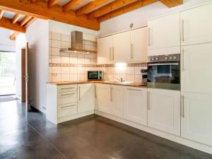 uma cozinha com armários brancos e um forno com placa de fogão em Premium Cottage in Florennes near Private Fish Lake Forest em Florennes