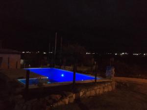a blue swimming pool at night with lights in the background at CABAÑA EN TANTI in Tanti