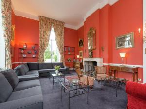 uma sala de estar com paredes vermelhas, um sofá e uma lareira em Beautiful manor house in a park near Rochefort em Forrières